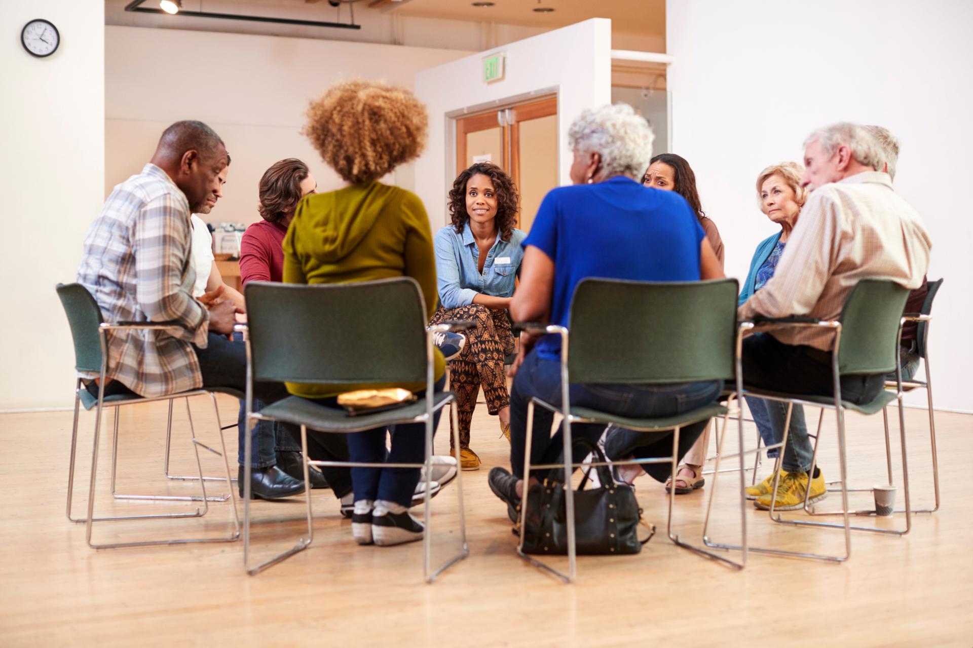 Groups of seated adults in a circle having a discussion